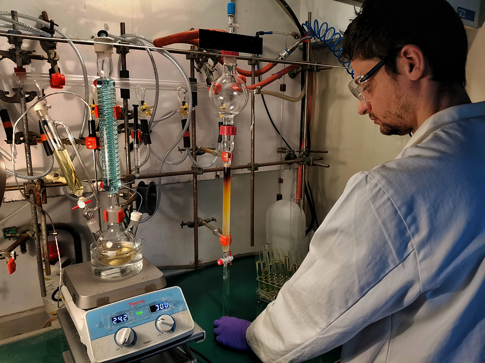 Un scientifique purifiant une molécule par chromatographie pendant qu'une autre molécule est synthétisée, à gauche